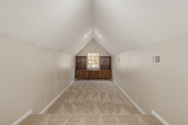 bonus room with light colored carpet and a textured ceiling