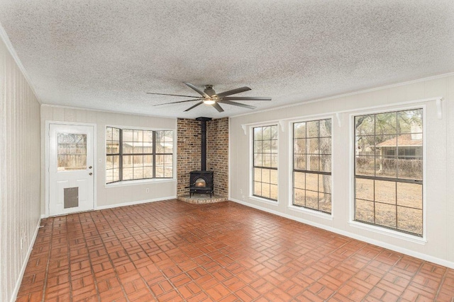 unfurnished living room with brick floor, a wood stove, and a healthy amount of sunlight