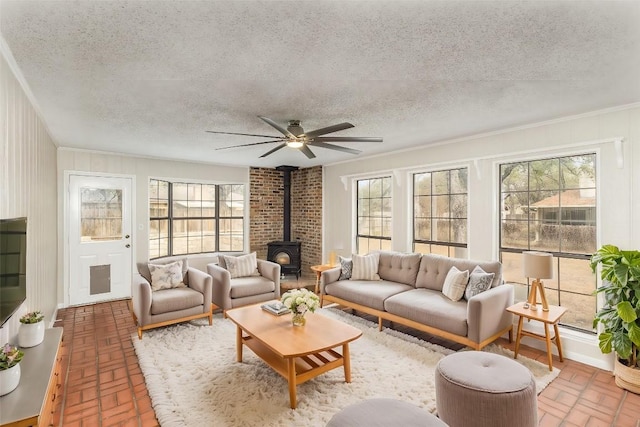 living room featuring a wood stove, brick floor, plenty of natural light, and a textured ceiling