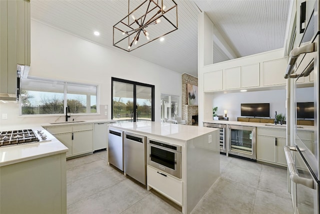 kitchen with beverage cooler, stainless steel appliances, a fireplace, a sink, and light countertops