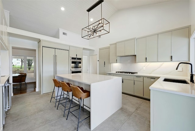 kitchen featuring built in fridge, a breakfast bar area, visible vents, a sink, and high vaulted ceiling