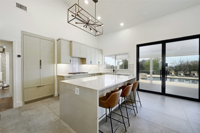 kitchen featuring an inviting chandelier, a high ceiling, light countertops, and a sink