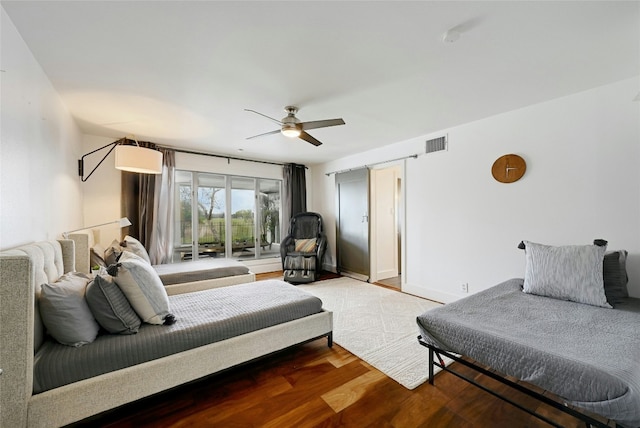 bedroom with ceiling fan, wood finished floors, visible vents, and baseboards