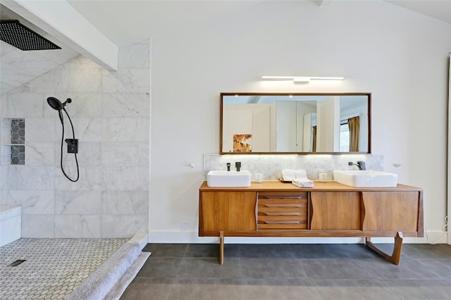 bathroom featuring lofted ceiling with beams, double vanity, tiled shower, and a sink