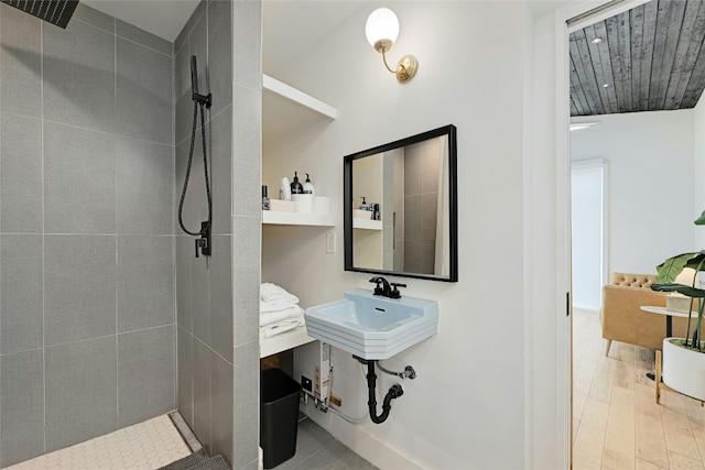 bathroom with tiled shower and wood finished floors