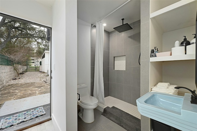 bathroom featuring a sink, toilet, and tiled shower