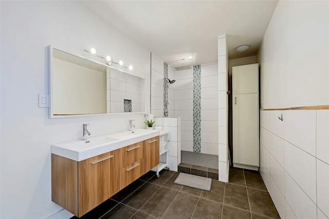 bathroom with a sink, tile walls, tile patterned floors, double vanity, and walk in shower