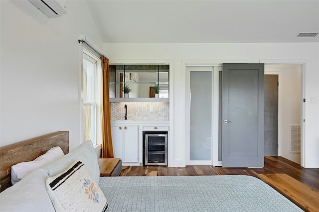 bedroom featuring indoor wet bar, beverage cooler, visible vents, and dark wood-style flooring