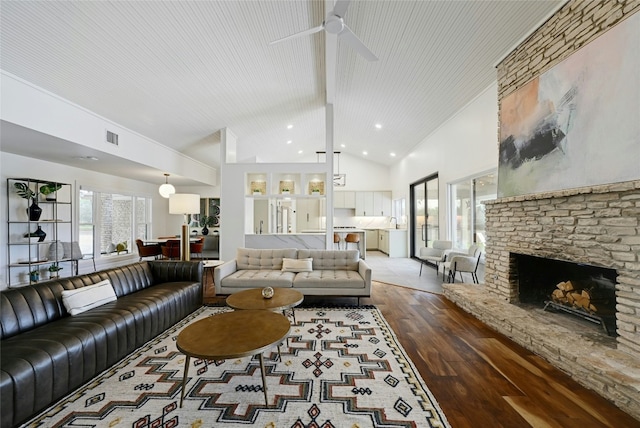 living area featuring visible vents, hardwood / wood-style flooring, a fireplace, high vaulted ceiling, and recessed lighting