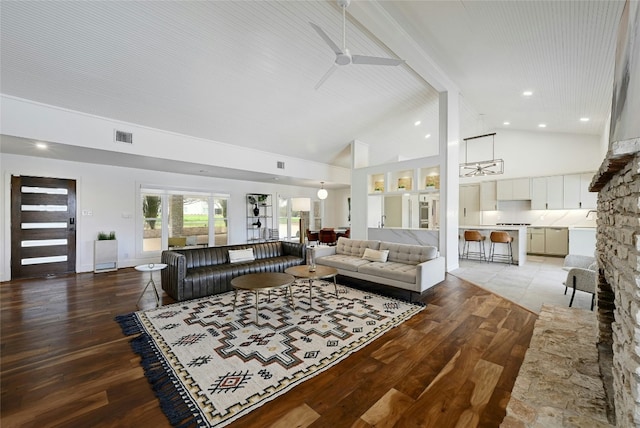 living area with high vaulted ceiling, visible vents, a fireplace, and light wood-style flooring