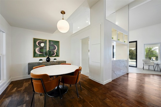 dining space with wood-type flooring, a high ceiling, and baseboards