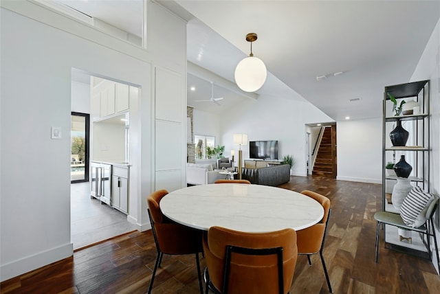 dining room featuring dark wood-style floors, high vaulted ceiling, stairway, and baseboards