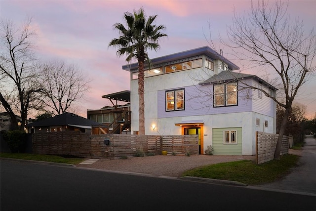 view of front of home with gravel driveway, a fenced front yard, and stucco siding