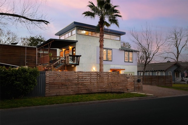 property exterior at dusk with a fenced front yard and stucco siding