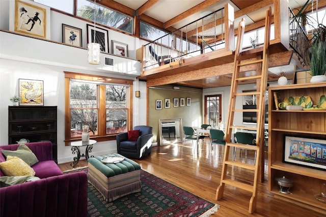 living area with a towering ceiling, plenty of natural light, visible vents, and wood finished floors