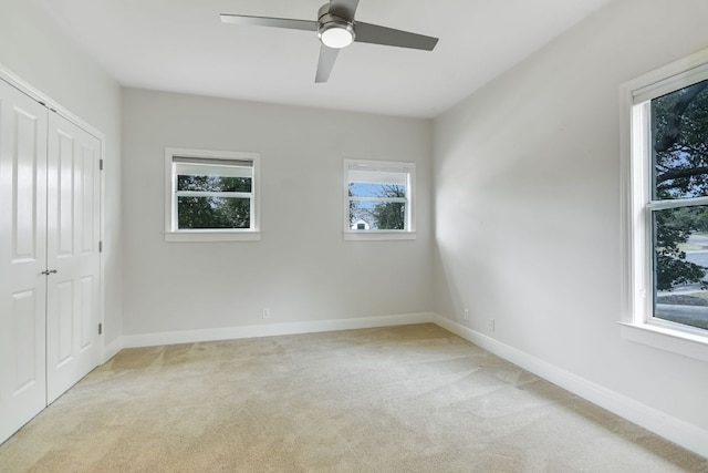 unfurnished bedroom featuring a closet, light colored carpet, and baseboards