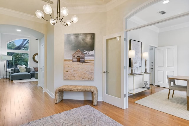 interior space featuring arched walkways, a notable chandelier, visible vents, ornamental molding, and hardwood / wood-style flooring