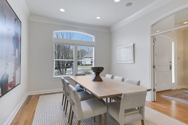 dining space with ornamental molding, light wood-type flooring, and baseboards