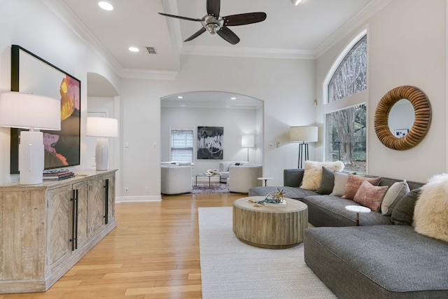 living area with visible vents, arched walkways, ornamental molding, a healthy amount of sunlight, and light wood-style floors