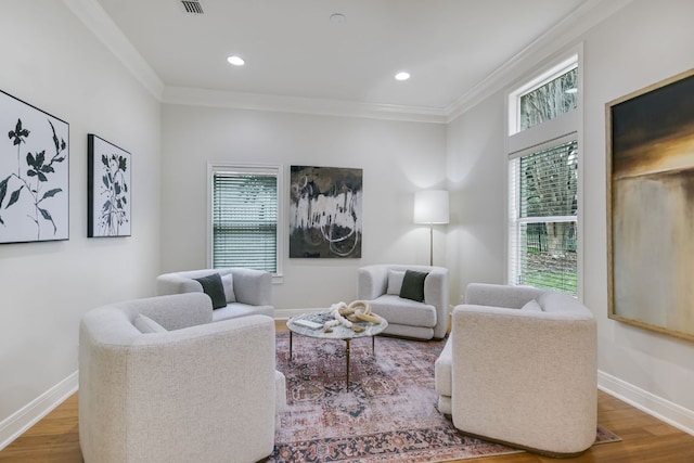 living room featuring a healthy amount of sunlight, wood finished floors, and crown molding