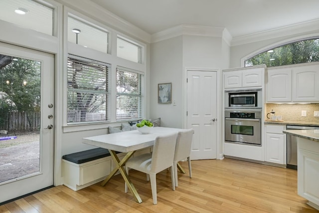 kitchen with white cabinetry, light wood-style floors, appliances with stainless steel finishes, breakfast area, and crown molding