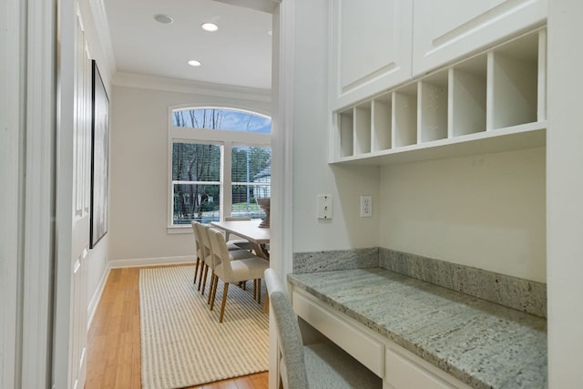 interior space featuring light stone counters, crown molding, open shelves, white cabinets, and light wood-type flooring