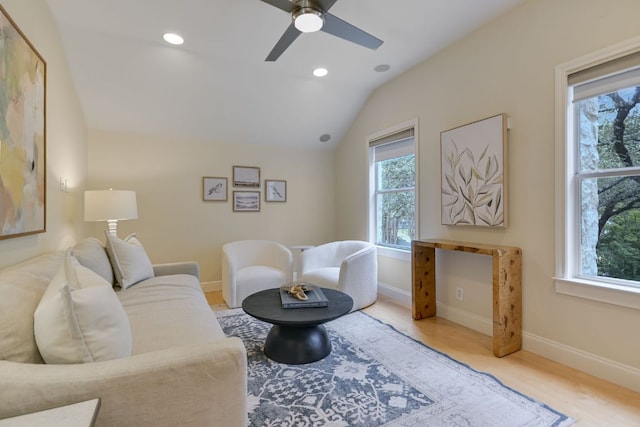 living room featuring plenty of natural light, vaulted ceiling, baseboards, and wood finished floors