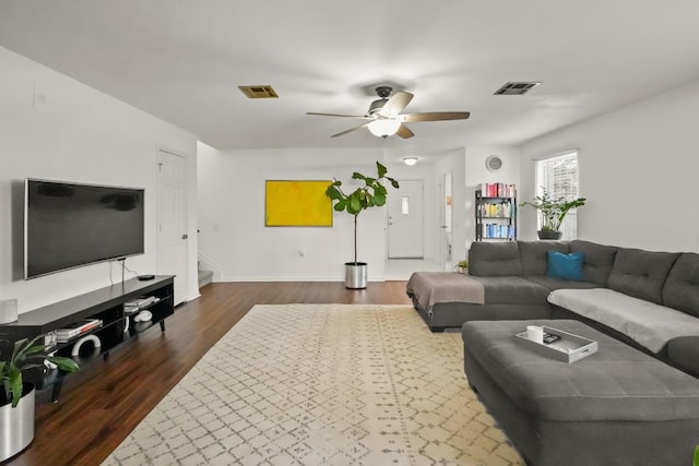 living room with stairway, a ceiling fan, visible vents, and dark wood-style flooring