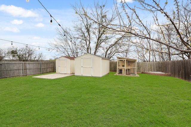 view of yard featuring a storage shed, a fenced backyard, and an outbuilding