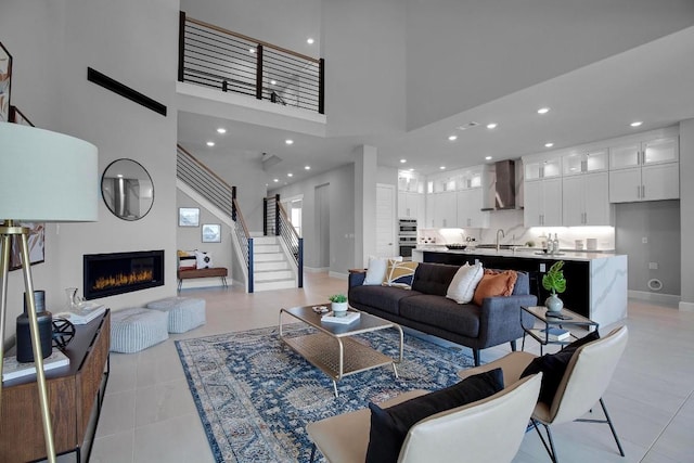 16909 Roselin Dr, Austin, TX 78738 - living room featuring a glass covered fireplace, a high ceiling, light tile patterned floors, baseboards, and stairway