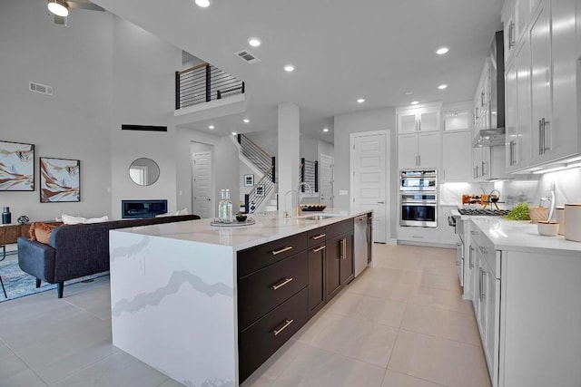 kitchen featuring a glass covered fireplace, white cabinets, visible vents, and a sink