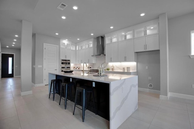 16909 Roselin Dr, Austin, TX 78738 - kitchen featuring wall chimney range hood, double oven, baseboards, white cabinetry, and light tile patterned flooring