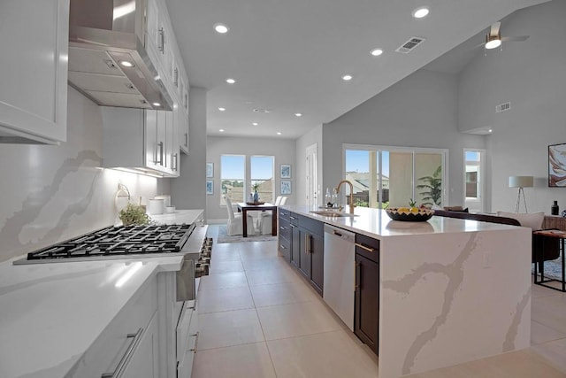 kitchen featuring visible vents, a sink, open floor plan, range hood, and appliances with stainless steel finishes