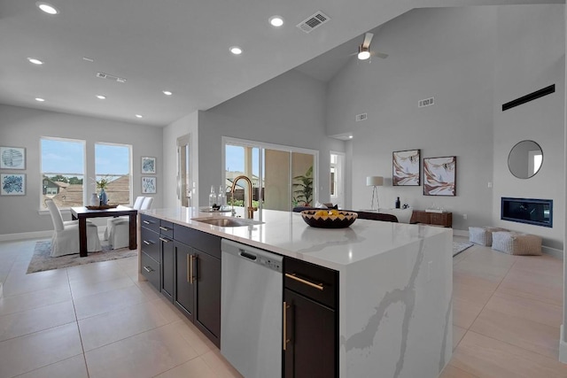 kitchen with a glass covered fireplace, light tile patterned floors, a sink, dishwasher, and open floor plan