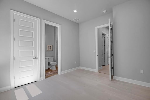 unfurnished bedroom with visible vents, connected bathroom, light wood-style floors, and baseboards