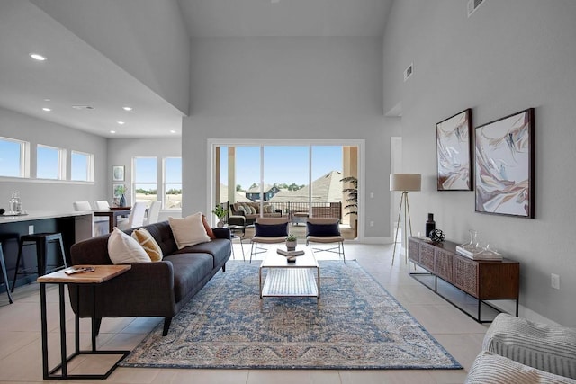 living area with light tile patterned flooring, recessed lighting, baseboards, and a towering ceiling