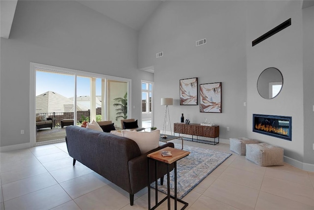 living area featuring a glass covered fireplace, light tile patterned flooring, baseboards, and visible vents