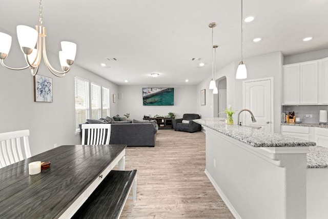 dining area featuring visible vents, arched walkways, an inviting chandelier, light wood-type flooring, and recessed lighting