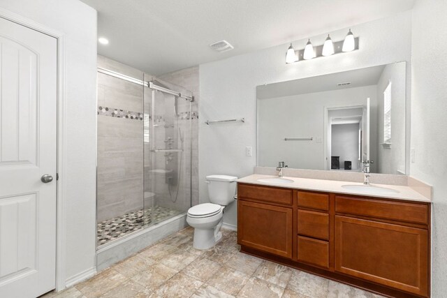 full bathroom with double vanity, a stall shower, a sink, and toilet