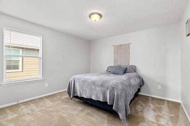 bedroom featuring light colored carpet, a textured ceiling, and baseboards