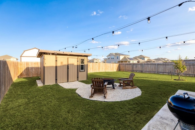 view of yard with an outdoor fire pit, a fenced backyard, an outdoor structure, and a storage unit