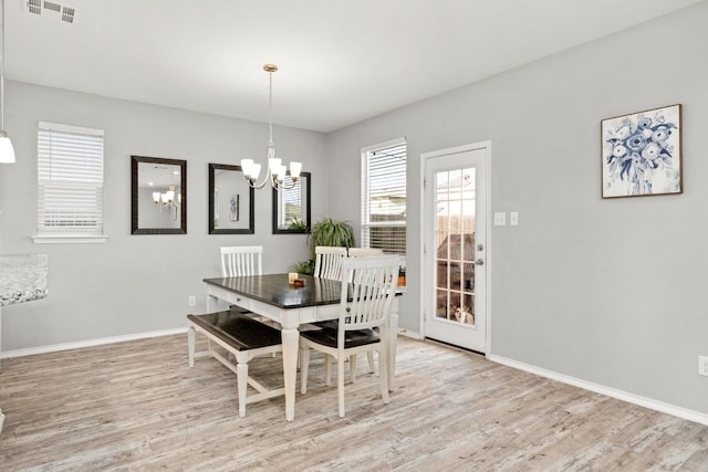 dining area featuring light wood finished floors, baseboards, visible vents, and an inviting chandelier