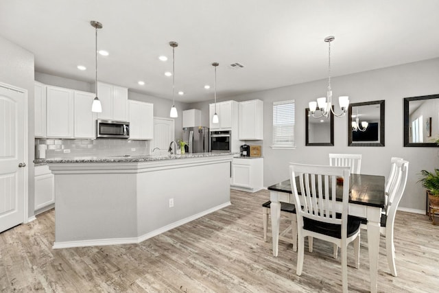 kitchen with visible vents, a kitchen island with sink, appliances with stainless steel finishes, and light wood-style flooring