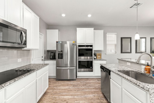 kitchen featuring light wood-style flooring, a sink, visible vents, appliances with stainless steel finishes, and tasteful backsplash