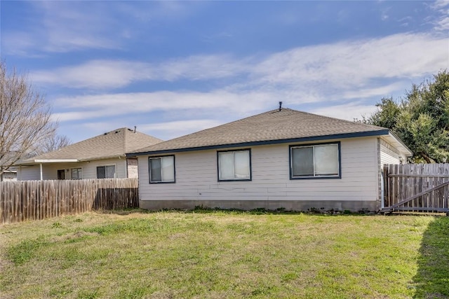 back of property featuring fence, a lawn, and roof with shingles