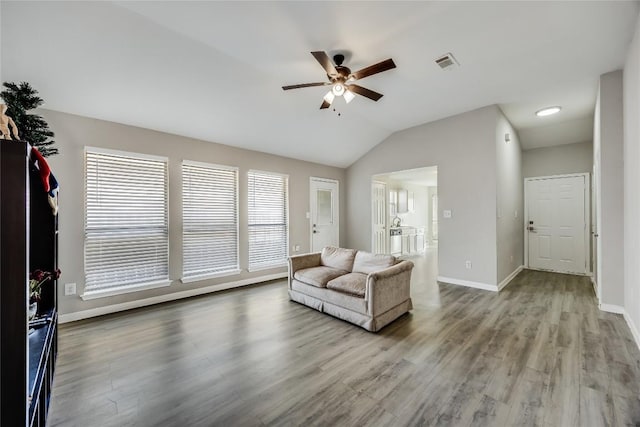 living area with ceiling fan, lofted ceiling, wood finished floors, visible vents, and baseboards