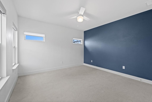 carpeted spare room with ceiling fan, visible vents, and baseboards