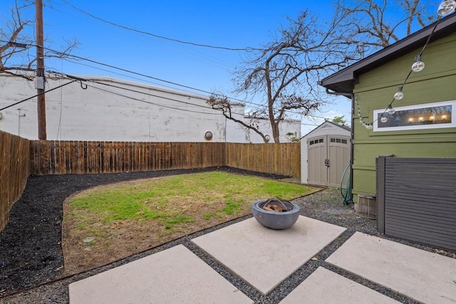 view of yard featuring a fire pit, a fenced backyard, an outdoor structure, a patio area, and a shed