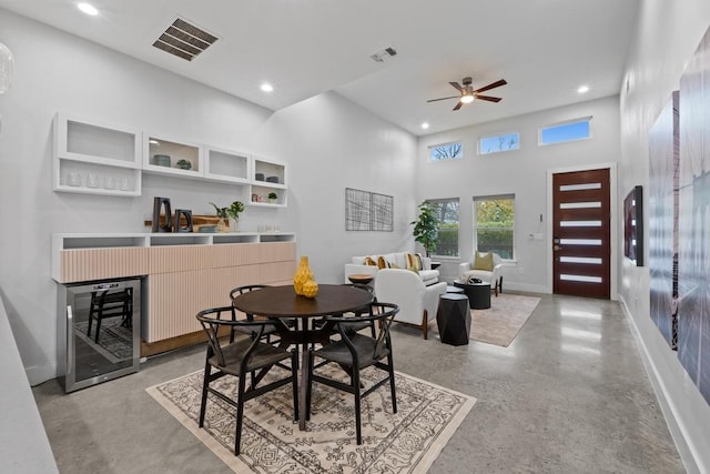 dining room with wine cooler, a high ceiling, visible vents, and baseboards