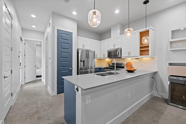 kitchen with a peninsula, a sink, appliances with stainless steel finishes, and concrete flooring